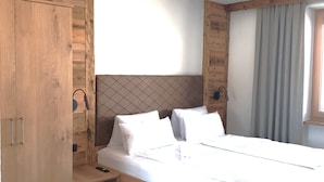 A wooden bed with white bedding, a small bedside table, and a wardrobe with a mirror. - Zedlacherhof (Matrei in Osttirol)