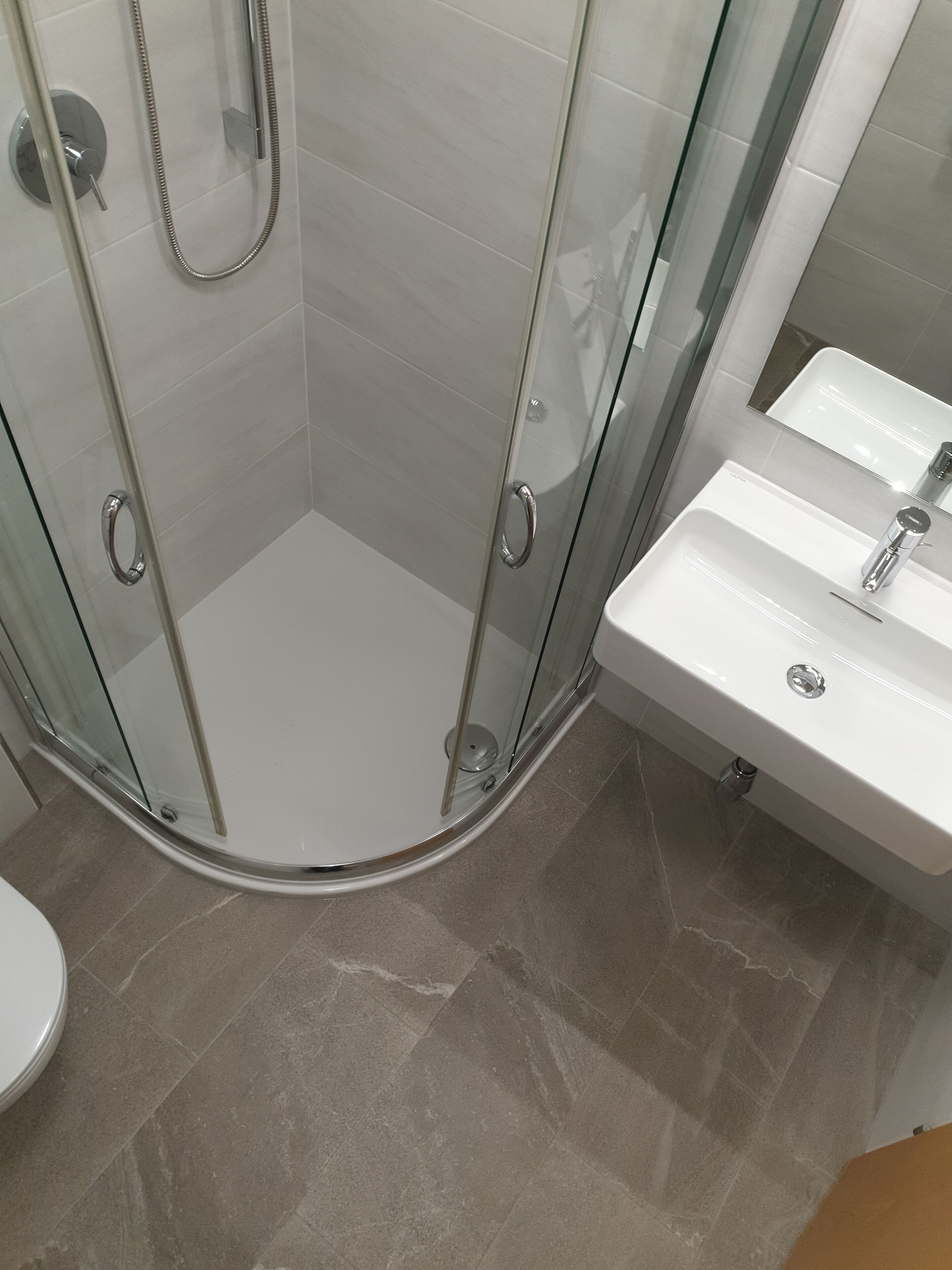 A bathroom with a glass-enclosed shower, a white sink, and a mirror above the sink.