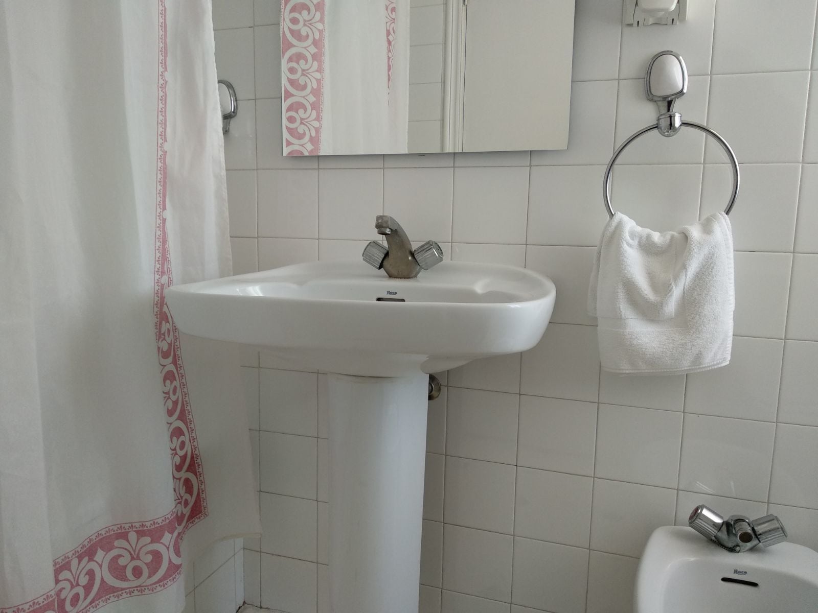 A bathroom with a white sink, a mirror, and a towel rack.