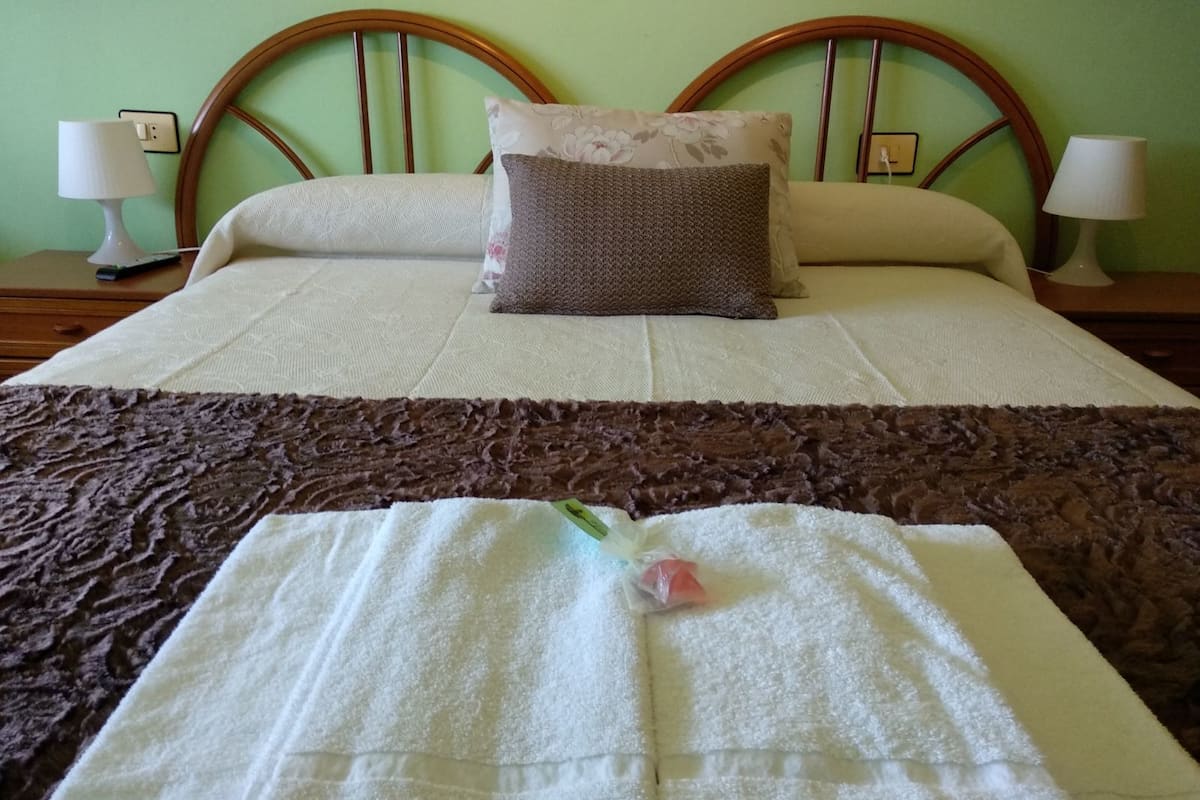 Una cama bien hecha con una colcha marrón con textura, una toalla blanca y una almohada decorativa.