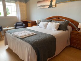 Habitación de hotel ordenada con una cama grande, un escritorio, una silla y una mesita.
