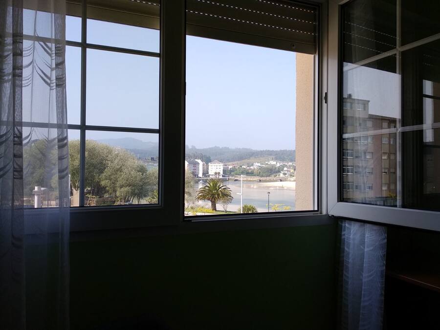 Una habitación con un ventanal grande que ofrece vistas a un paisaje urbano, con edificios y una masa de agua.
