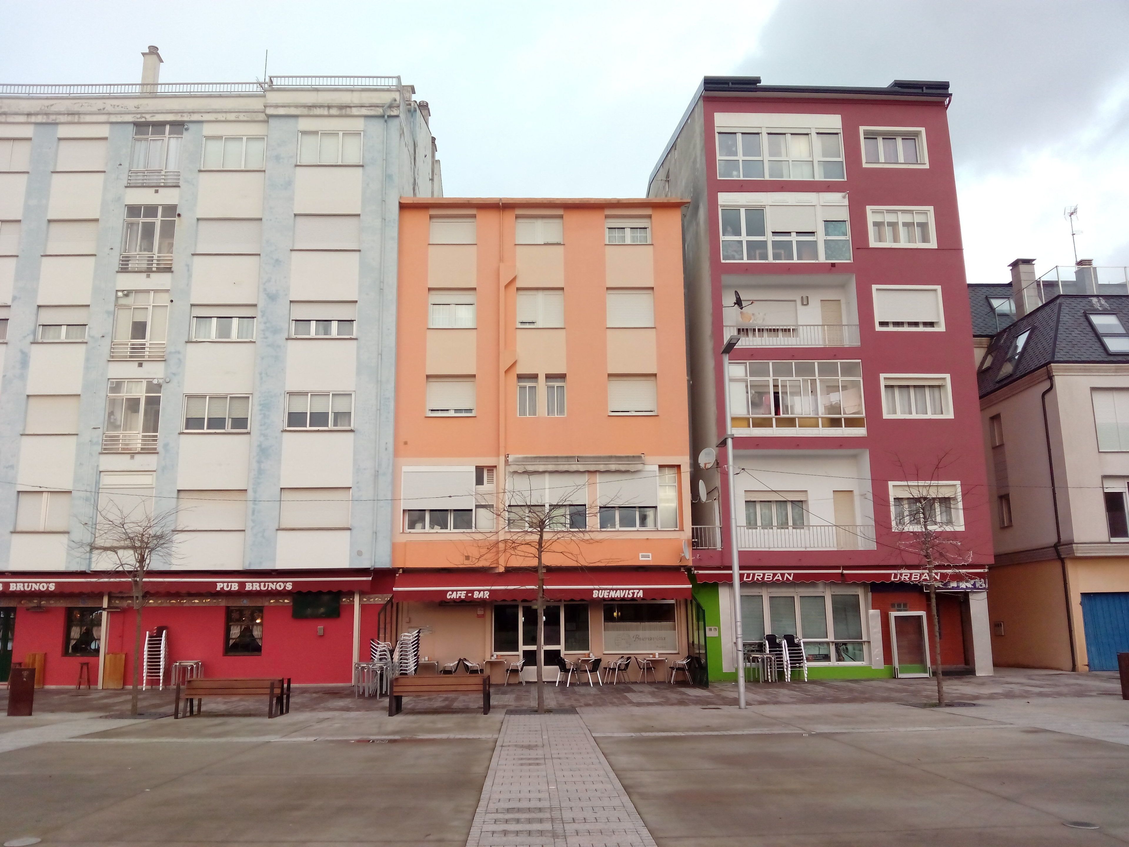 A row of multi-story buildings with various storefronts, including a pub and a cafe/bar.