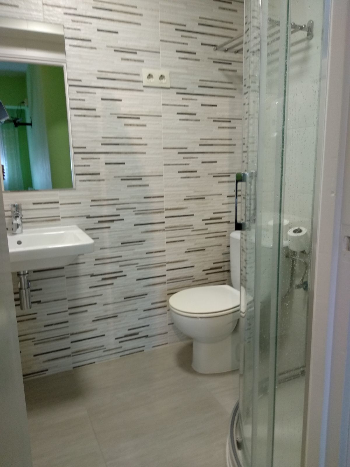 Un baño de diseño moderno, con inodoro, lavabo y cabina de ducha de vidrio.