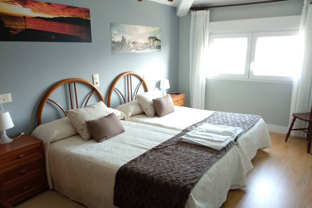 Una cama bien hecha con un edredón marrón, un cabecero de madera y dos mesitas de noche con lámparas.