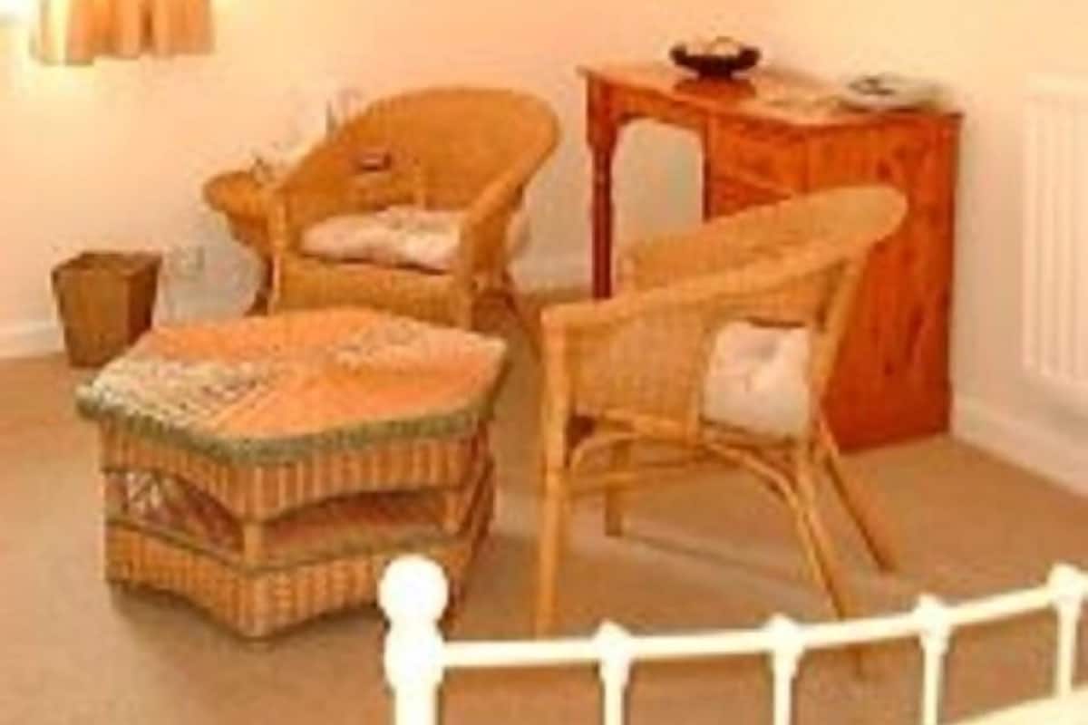 A cozy room with wicker furniture, a small table, and a lamp.