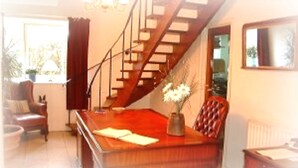 A room with a wooden staircase, a dining table with a vase of flowers, a chair, and a radiator. - The Old Malt House Hotel (Bath)