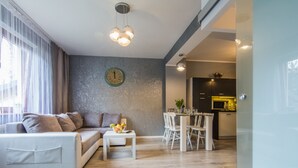 A modern living room with a sofa, coffee table, and dining area. - Apartamenty hoteLOVE przy Strumieniu (Karpacz)