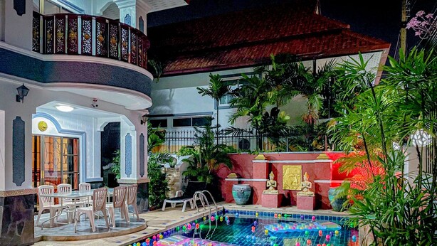 A multi-level indoor swimming pool with a tiled floor, surrounded by lounge chairs and a decorative wall with statues. - Madee Villa - Pattaya Holiday House Walking Street (Pattaya)