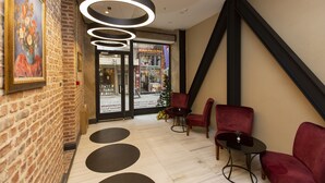 A lobby with brick walls, a wooden floor, and red chairs. - Premist Hotels Taksim - Special Class  (Istanbul)