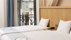 A hotel room with two beds, a wooden headboard, a hanging light fixture, and a view of the outside balcony. - Premist Hotels Taksim - Special Class  (Istanbul)