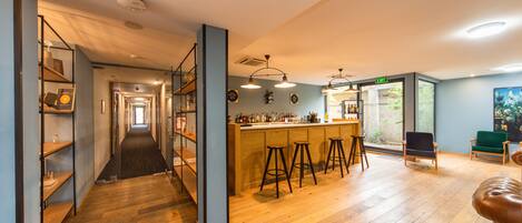 A spacious kitchen with wooden flooring, a bar area with stools, and a view of the outdoors through large windows.