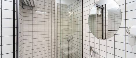 A modern bathroom with a glass-enclosed shower, a round mirror, and a white sink.