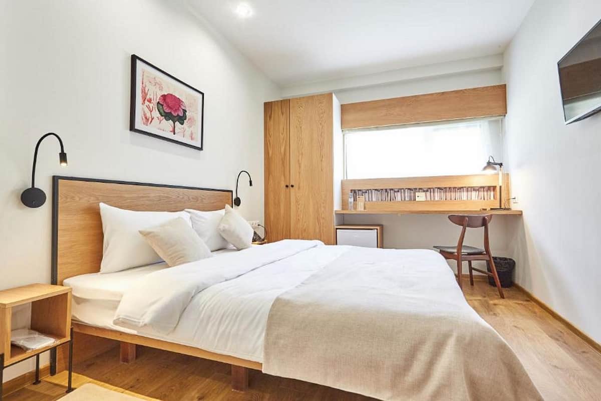 A bedroom with a wooden bed, a desk, and a chair.