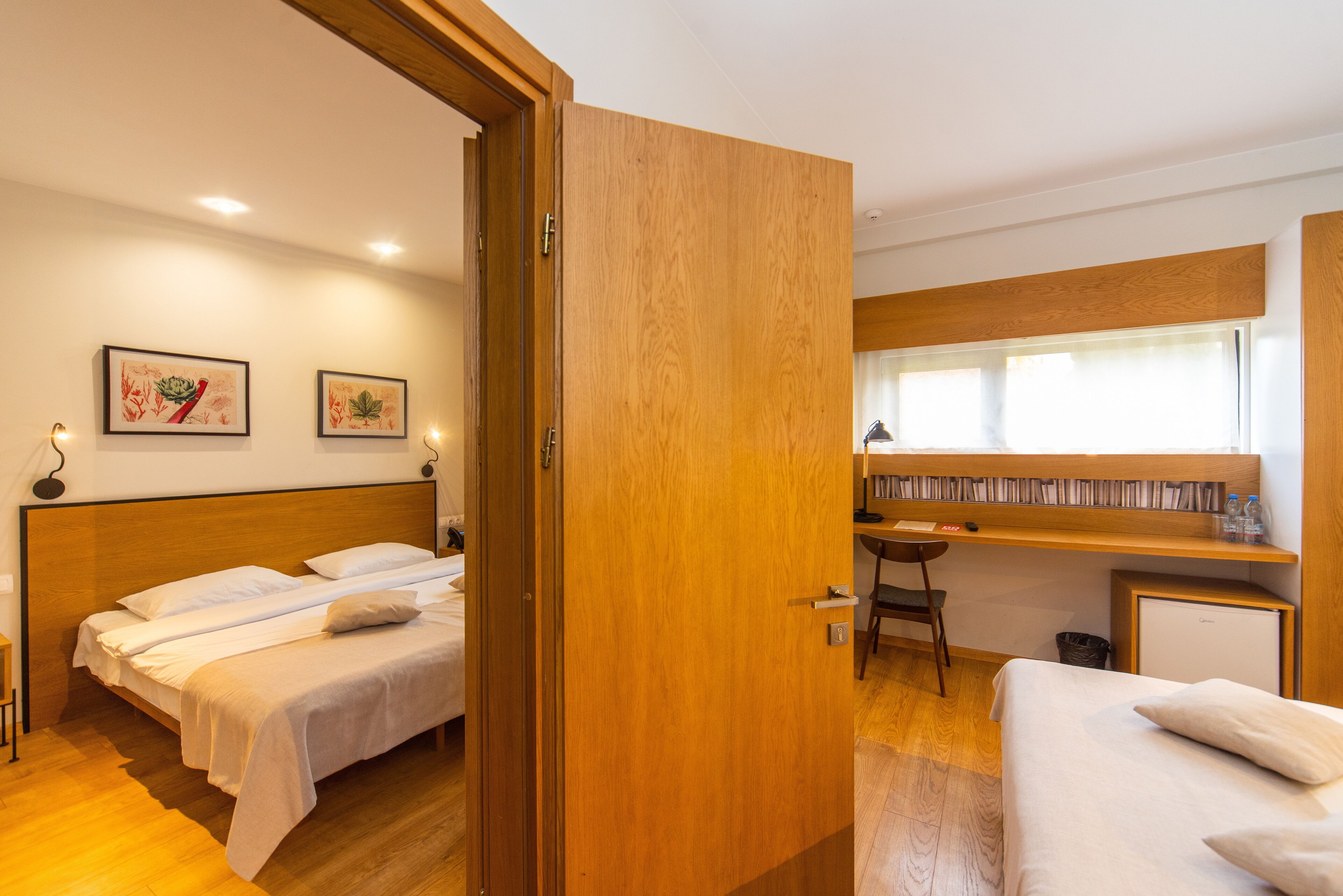 Une chambre d’hôtel avec deux lits, un bureau, une chaise et un petit réfrigérateur.