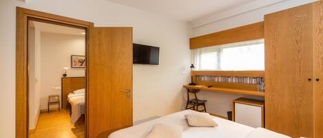 Un dormitorio con cama, escritorio, televisor y estantería.
