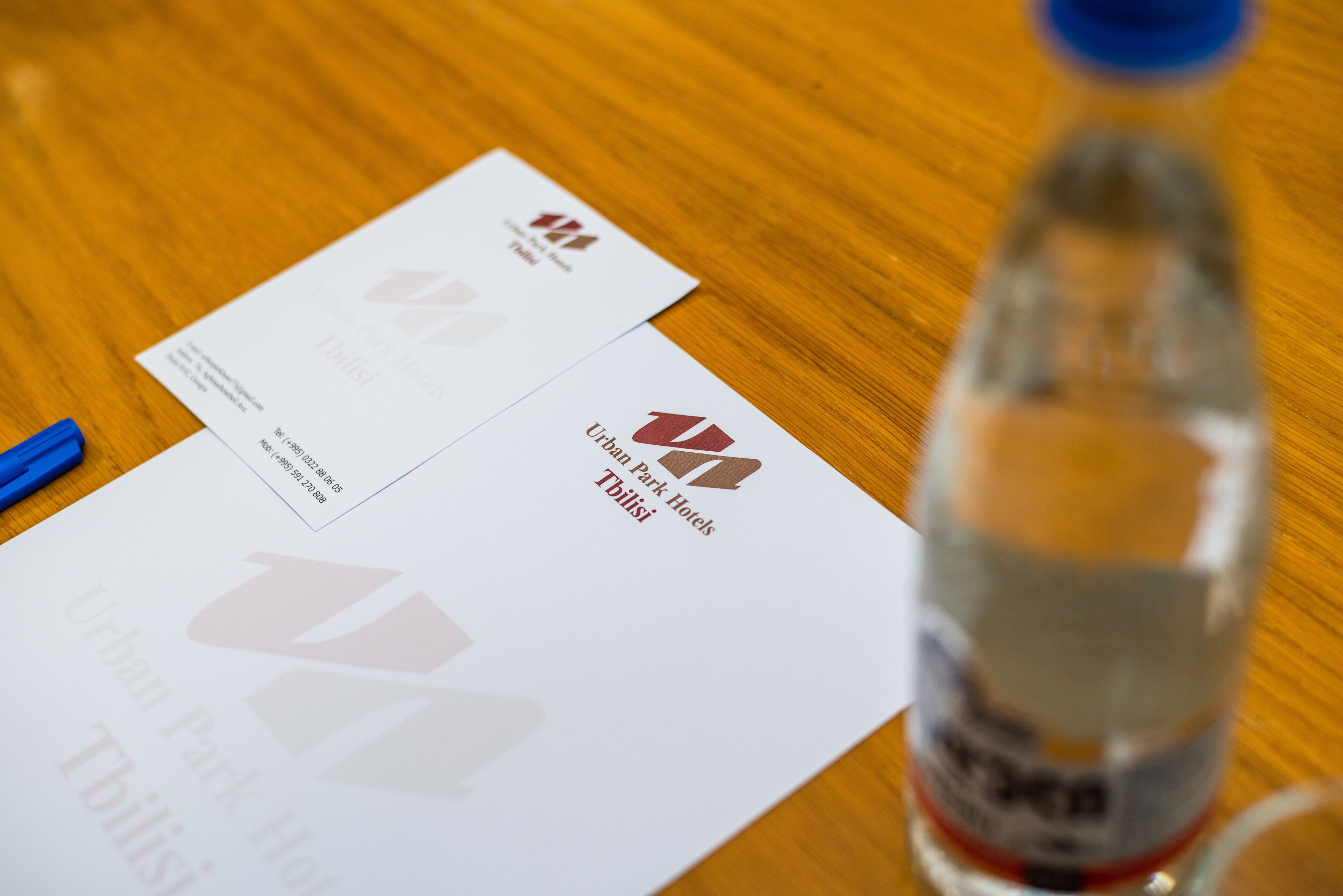 Business cards for Urban Park Hotels in Thulisi and a bottle of water on a wooden table.