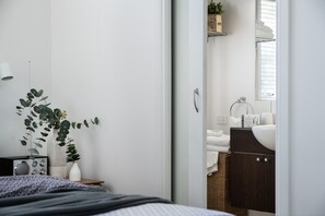 Un dormitorio con cama, mesita de noche y una planta.