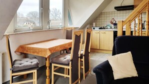 A cozy kitchen with a dining table and chairs, a wooden staircase, and a view of the outside. - Ferienwohnungen An der Sonnenwiese (Ostseebad Prerow)