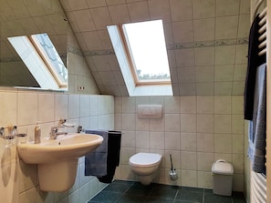 A bathroom with a sink, toilet, and a mirror. There is a skylight above the toilet. - Ferienwohnungen An der Sonnenwiese (Ostseebad Prerow)