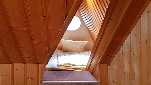 A wooden interior with a sloped ceiling leading to a bed area. - Ferienwohnungen An der Sonnenwiese (Ostseebad Prerow)
