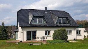 A two-story house with a dark tiled roof, a brick exterior, and a large front door. - Ferienwohnungen An der Sonnenwiese (Ostseebad Prerow)