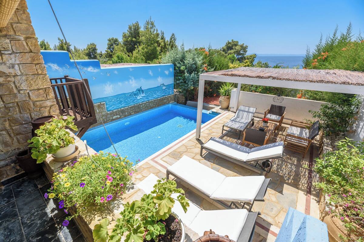 A swimming pool with a mural, lounge chairs, and potted plants.
