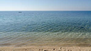 Une vue dégagée sur une plage aux eaux calmes, avec un bateau visible au loin.