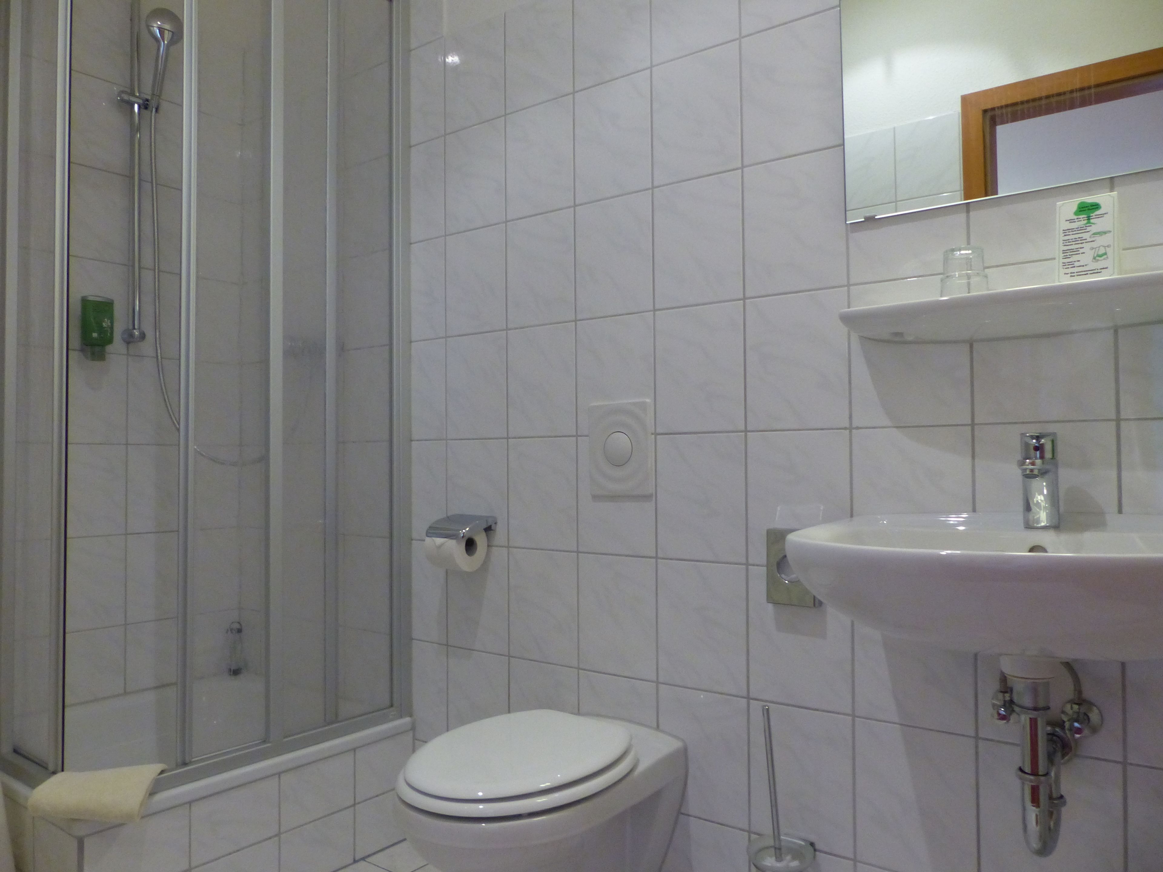 Un baño con ducha, inodoro, lavamanos y espejo.