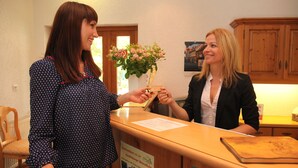 A reception desk with a wooden counter, a vase of flowers, and a sign indicating a local landmark. - Hotel zum Brauhaus Lüdde (Quedlinburg)