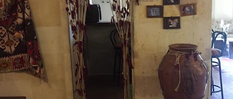 An interior space with a doorway leading to another room, a large vase, and a patterned rug.