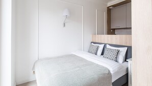 A bedroom with a bed, a bedside table, a lamp, and a wooden headboard. - Homewell Apartments Dominikańska (Poznan)