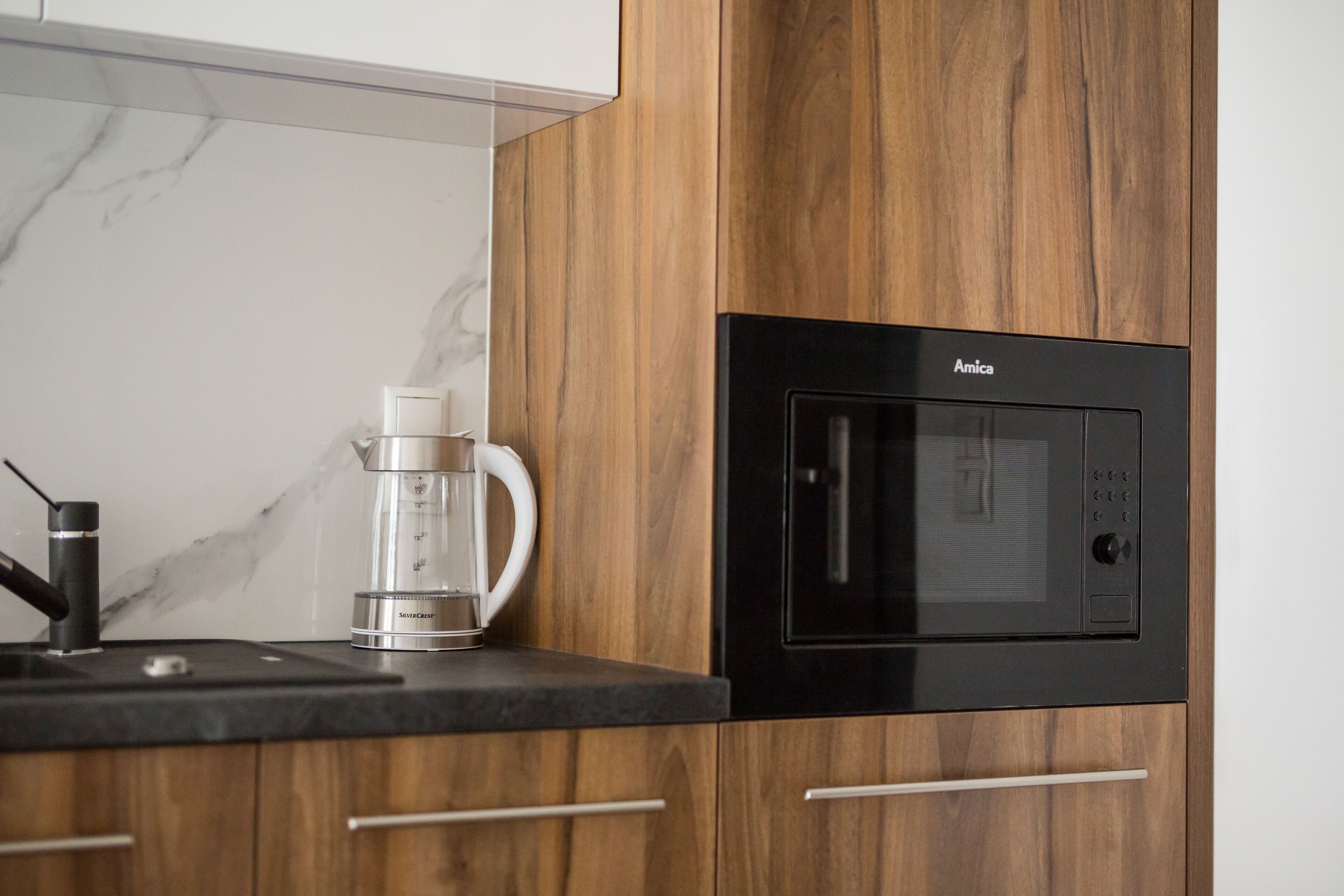 Cozinha equipada com micro-ondas, cafeteira e armários de madeira.