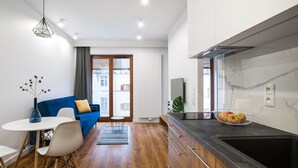 A modern kitchen with a black countertop, a sink, and a window overlooking a cityscape. - Homewell Apartments Dominikańska (Poznan)