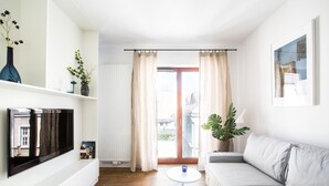 A modern living room with a flat-screen TV, a sofa, a coffee table, and a potted plant. - Homewell Apartments Dominikańska (Poznan)