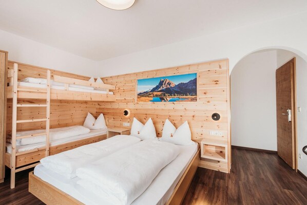 Habitación con literas de madera y un cuadro con paisaje de montaña en la pared.
