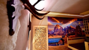 Een kamer met een houten paneel, een groot schilderij van een berglandschap en een houten bank.