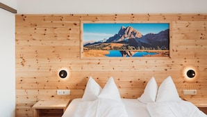 Een slaapkamer met een houten wandpaneel, een bed met wit beddengoed en een lijst met een landschapsafbeelding erboven.