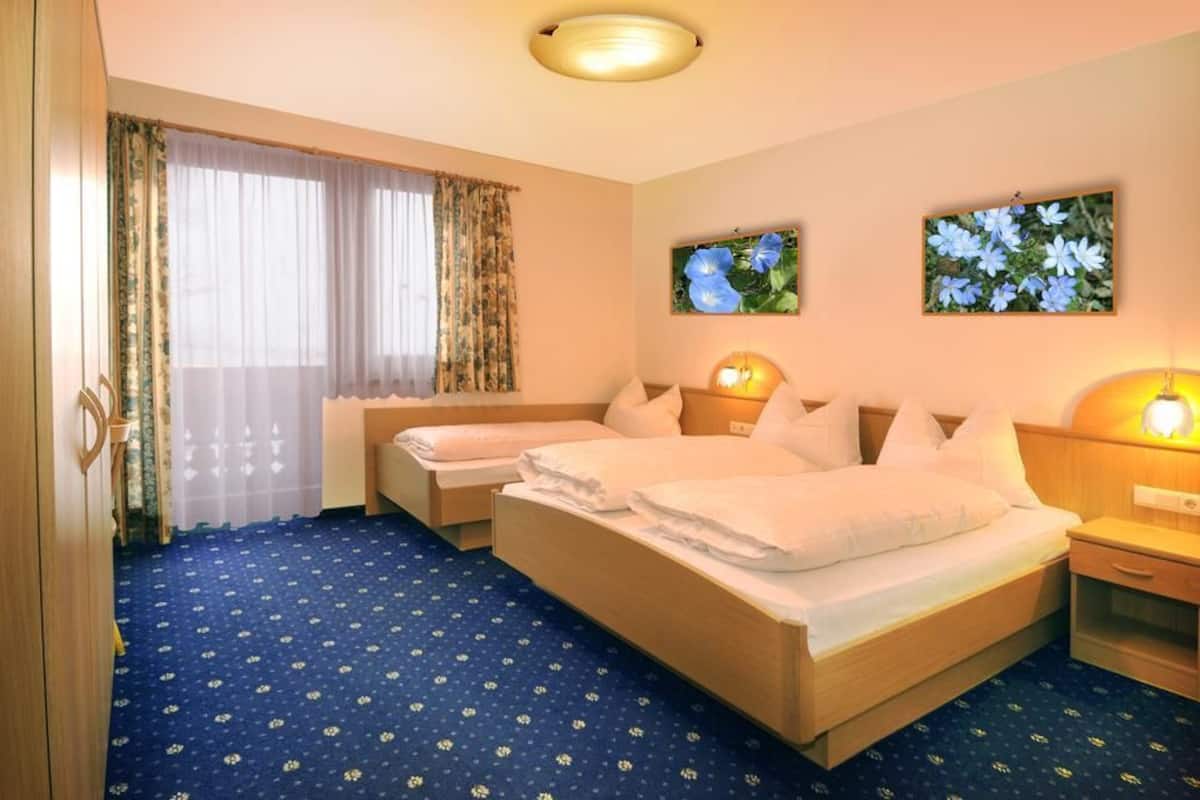 Une chambre d’hôtel avec deux lits, une tête de lit en bois, une table de chevet et une moquette bleue.