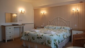 A bedroom with a bed, bedside tables, a desk, a chair, and a mirror. - La Michele (St. Martins)