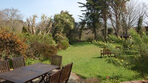 A garden with a wooden table and chairs, surrounded by various plants and trees. - La Michele (St. Martins)