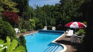 A swimming pool with a blue interior, surrounded by greenery and white lounge chairs. - La Michele (St. Martins)