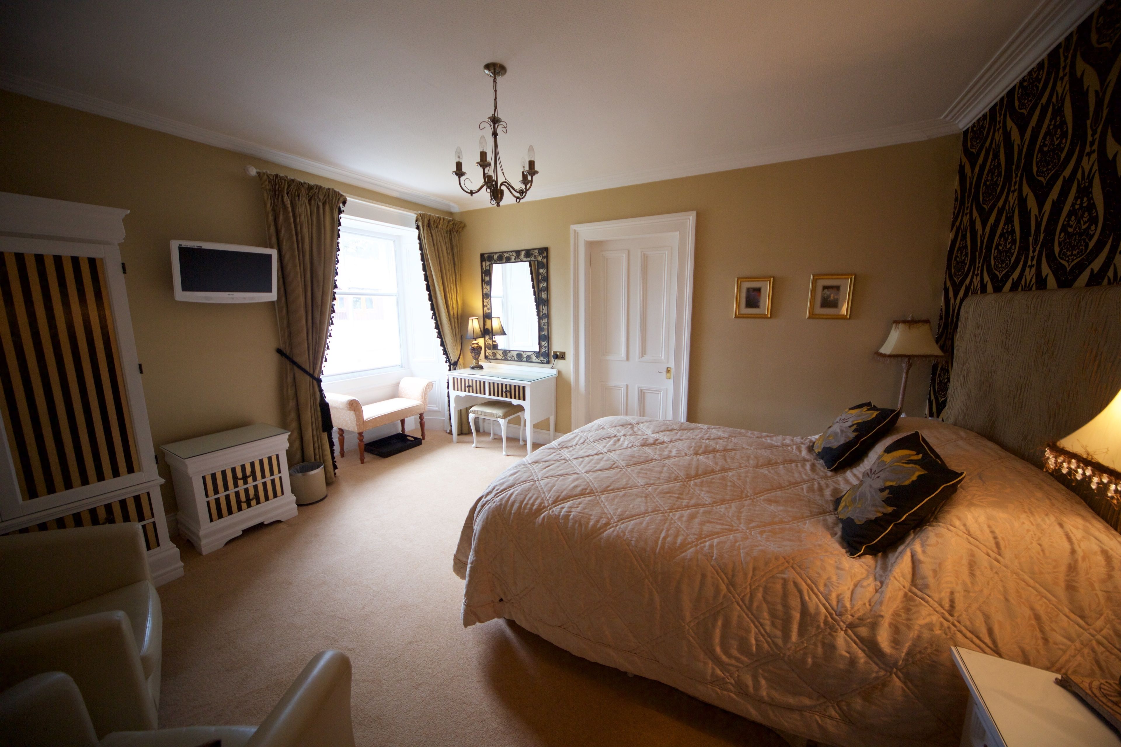 A bedroom with a large bed, a desk, a chair, and a crib.