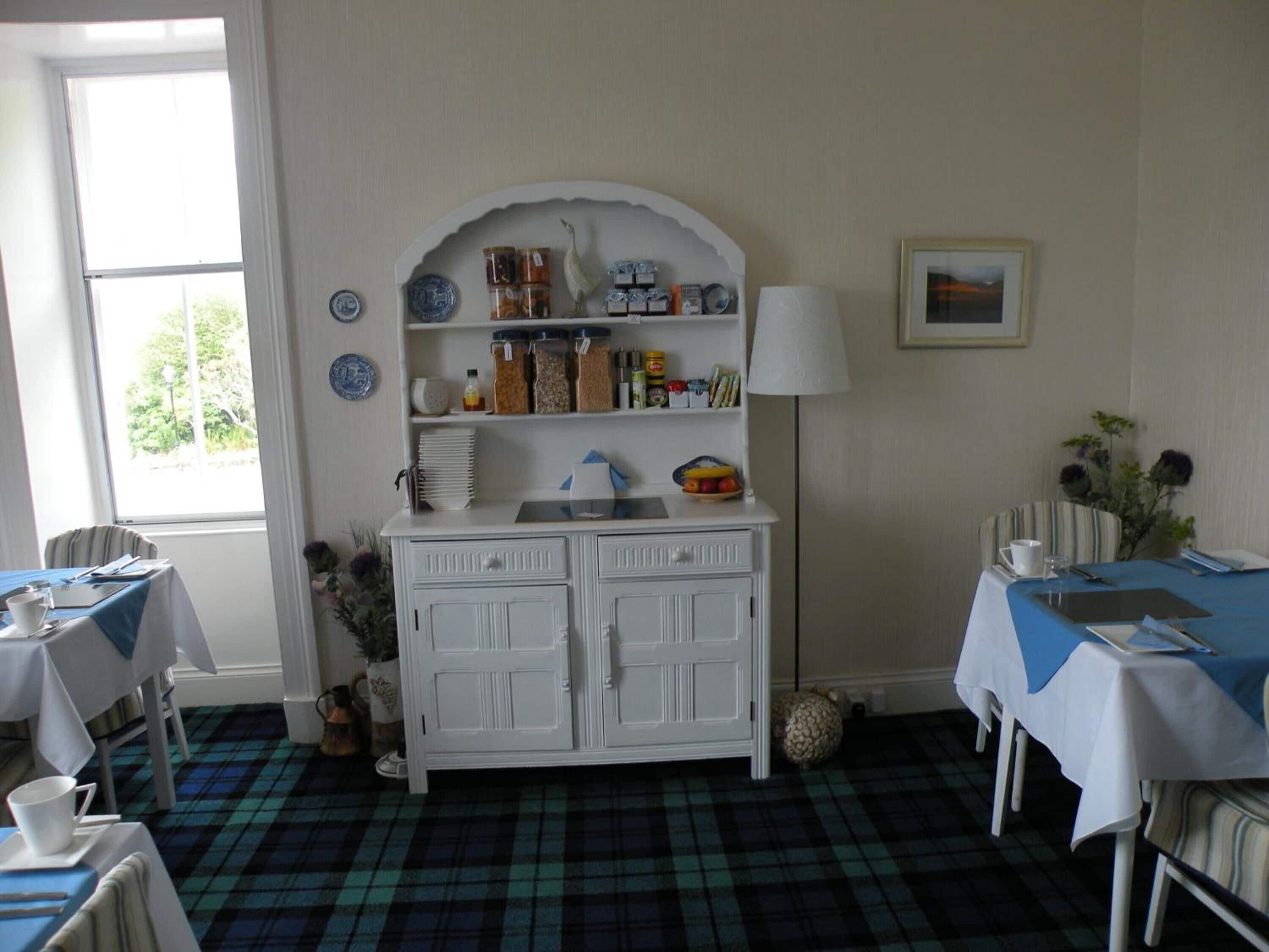A dining area with a white cabinet, a lamp, and a window with a view.