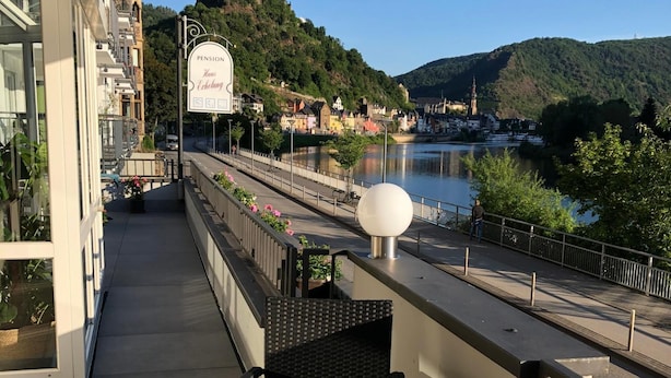 A balcony with a table set for dining, overlooking a river and a historic castle. - Haus Erholung (Cochem)