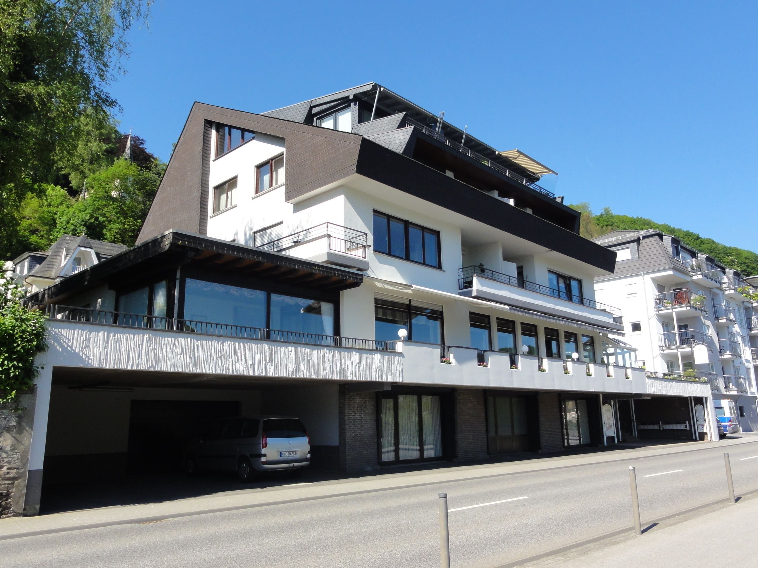Ein modernes, mehrstöckiges Hotel mit überdachter Parkgarage und heller Fassade.