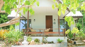 Una casa moderna con un porche cubierto, mobiliario exterior y una variedad de plantas.