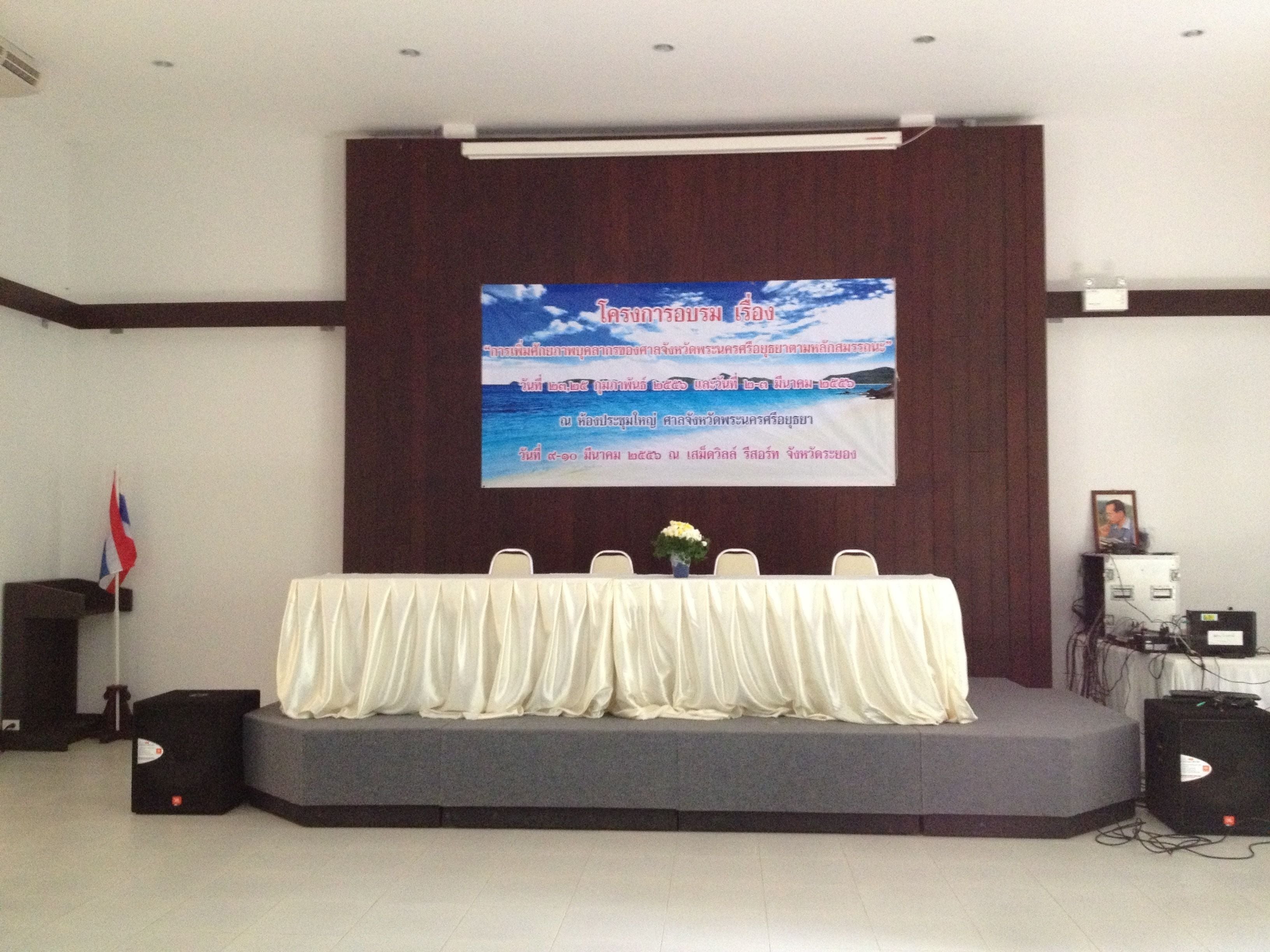 A conference room with a stage, a podium, a flag, and a banner.