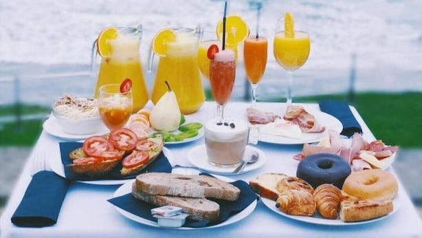 A table set with breakfast items and drinks by a seaside view.