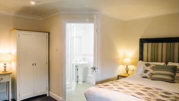 A bedroom with a bed, bedside tables, a wardrobe, and a bathroom visible through an open door.